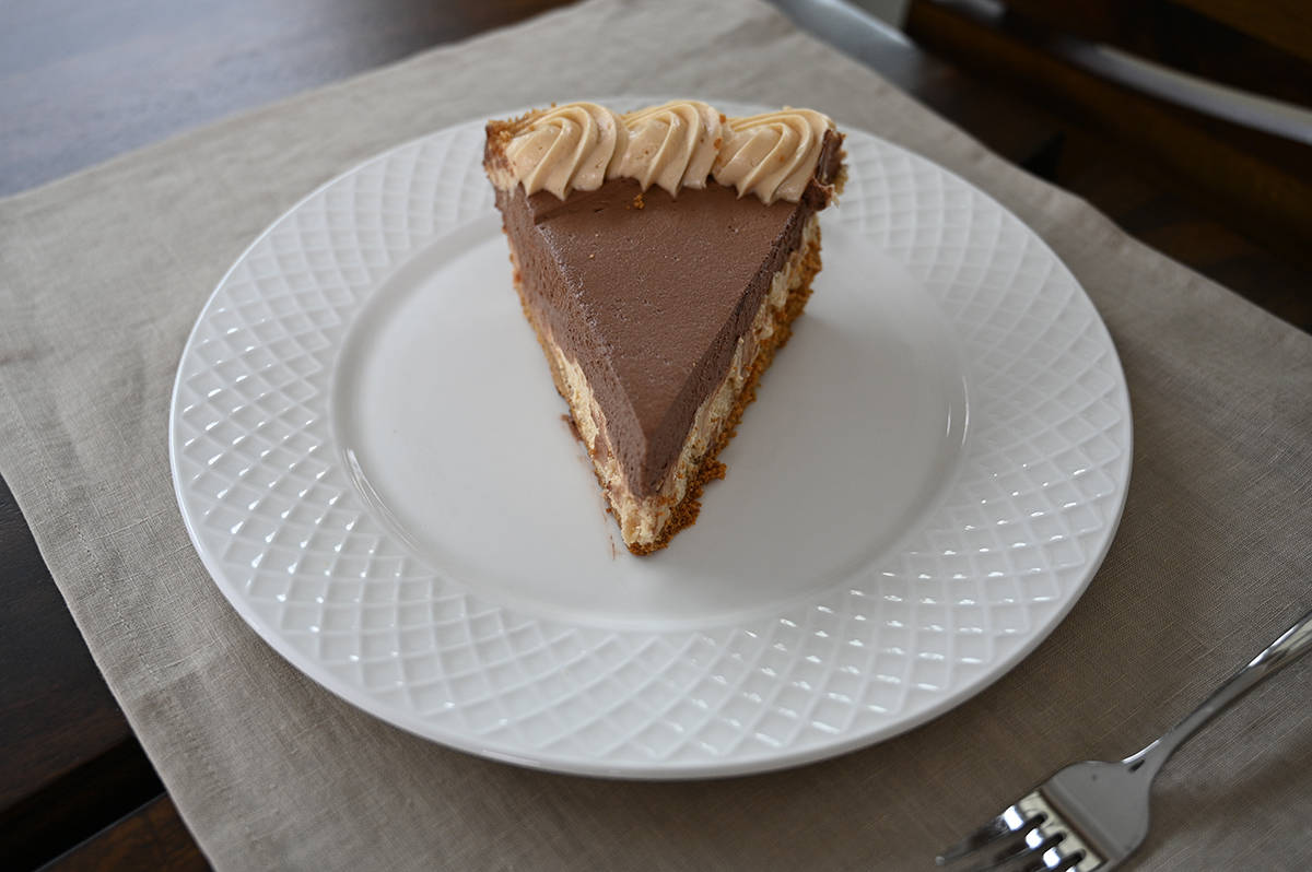 Top down image of one slice of pie served on a white plate with a fork beside it.