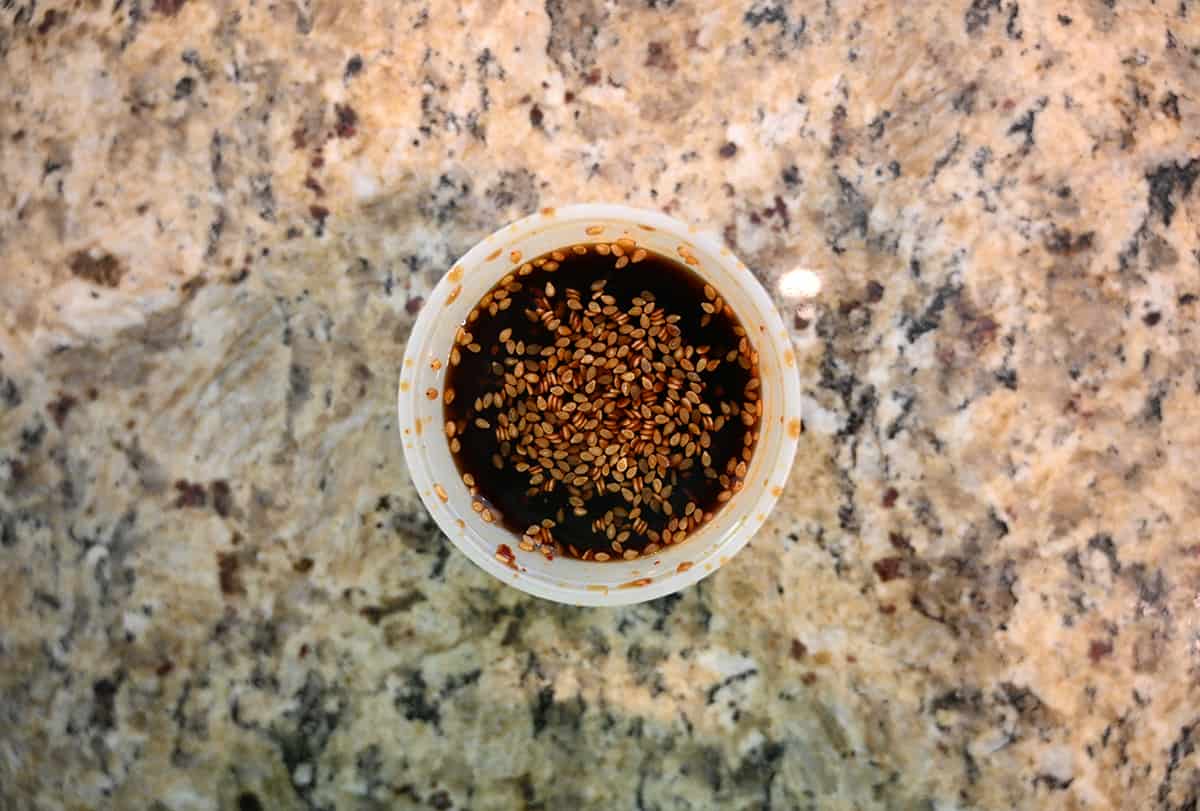 Top down image of an open container of poke sauce sitting on a table.