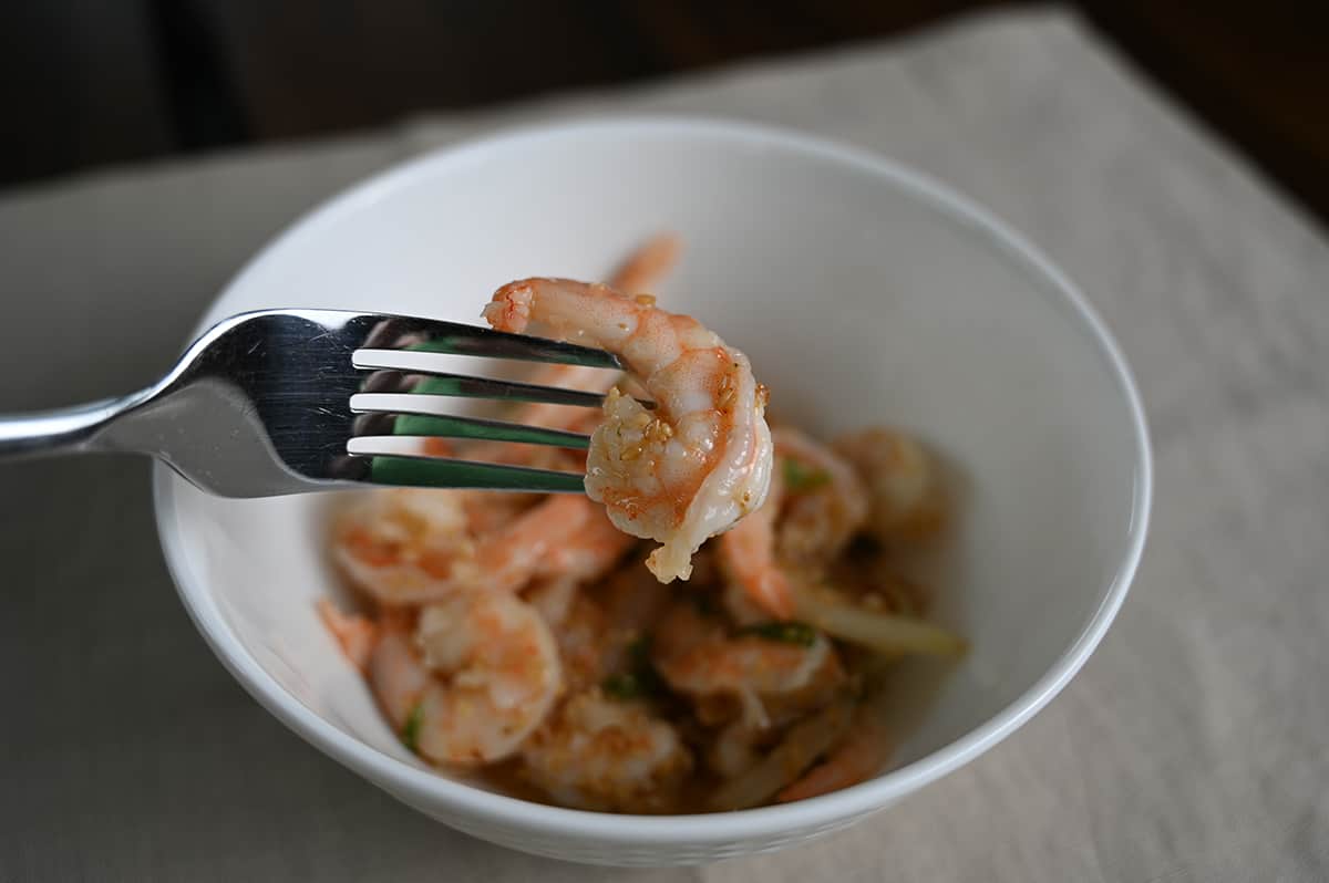 Image of a fork hovering over a bowl of Garlic Shrimp Poke, the fork has a piece of shrimp on it.