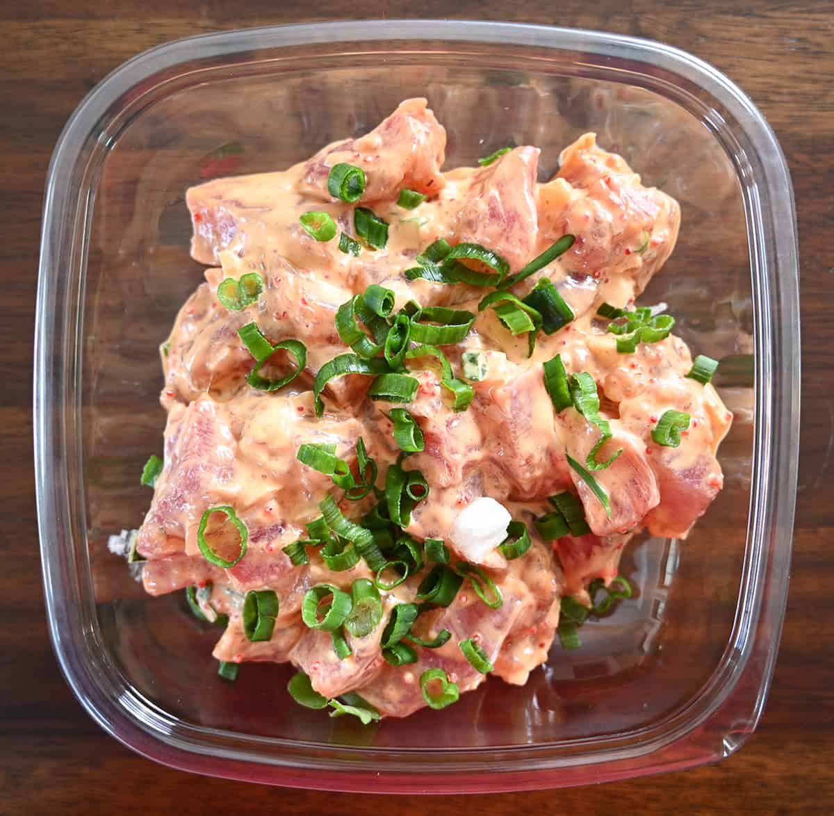 Top down image of an open container of the Spicy Ahi Poke. There are sesame seeds covering the poke.