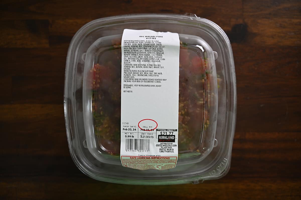 Top down image of an unopened container of Ahi Wasabi Poke sitting on a table.