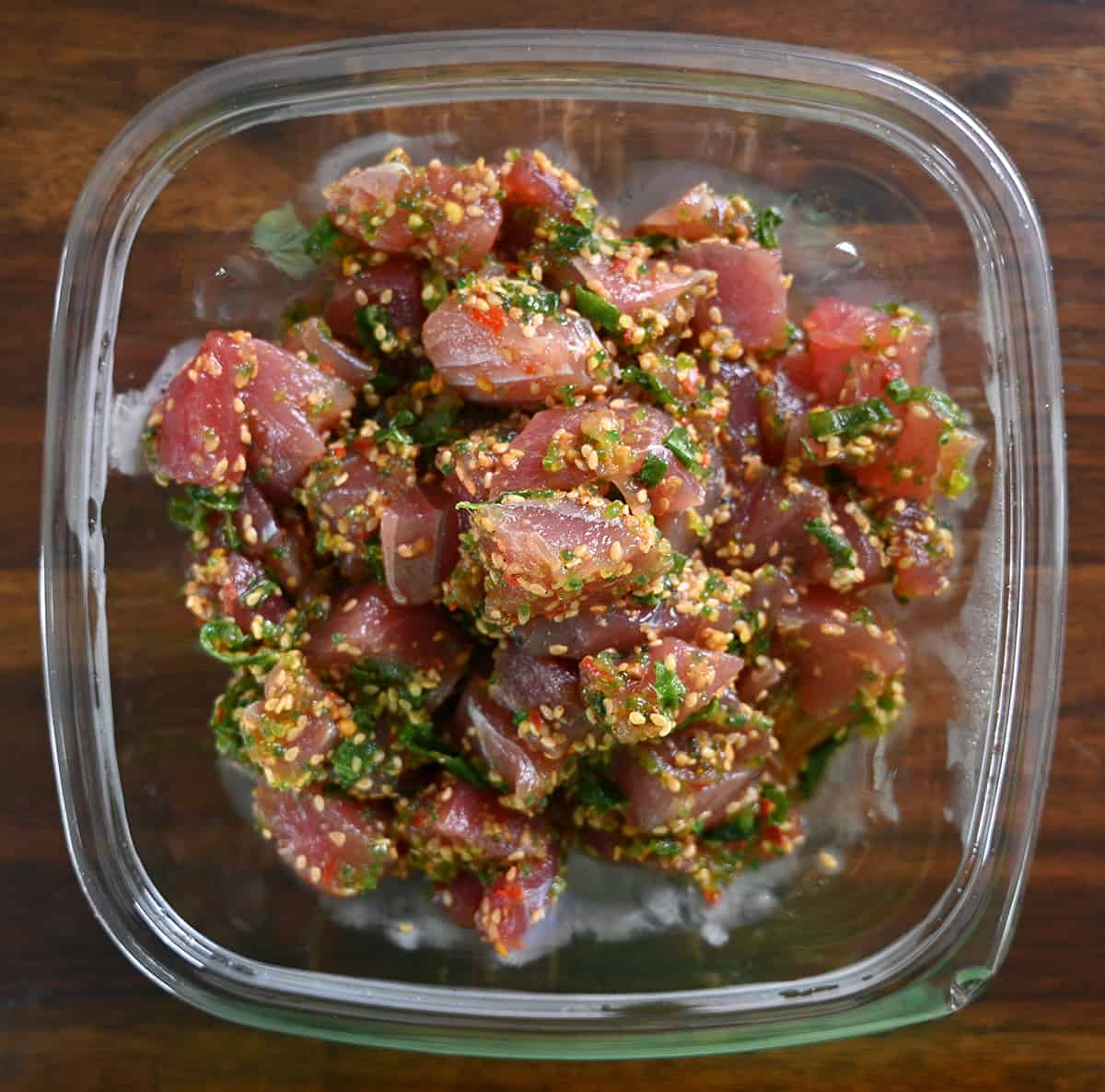 Top down image of an open container of the Ahi Wasabi Poke. There are sesame seeds covering the poke.