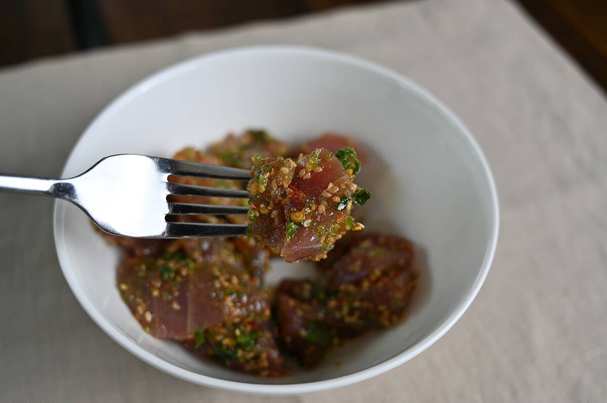 Image of a fork hovering over a bowl of Ahi Wasabi Poke, the fork has a piece of poke on it.