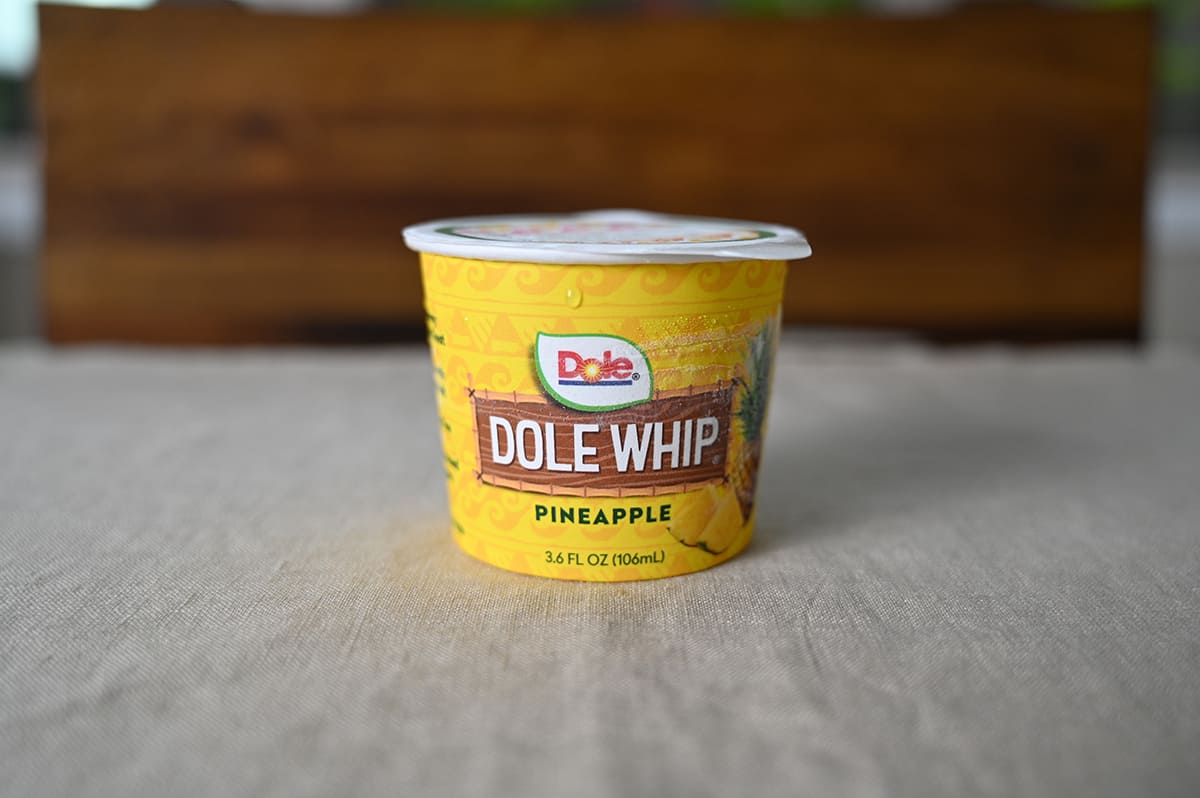 Side view image of one unopened individual cup of dole whip sitting on a table.