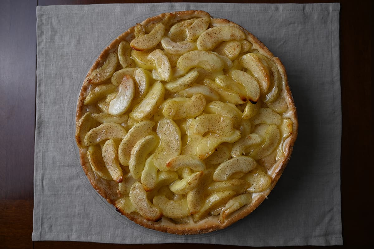 Top down closeup image of the apple cake out of the package, you can see many apples all across the top of the cake.