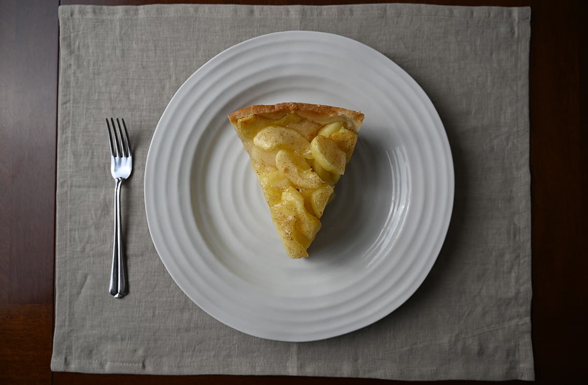 Top down image of one slice of apple cake served on a white plate. 