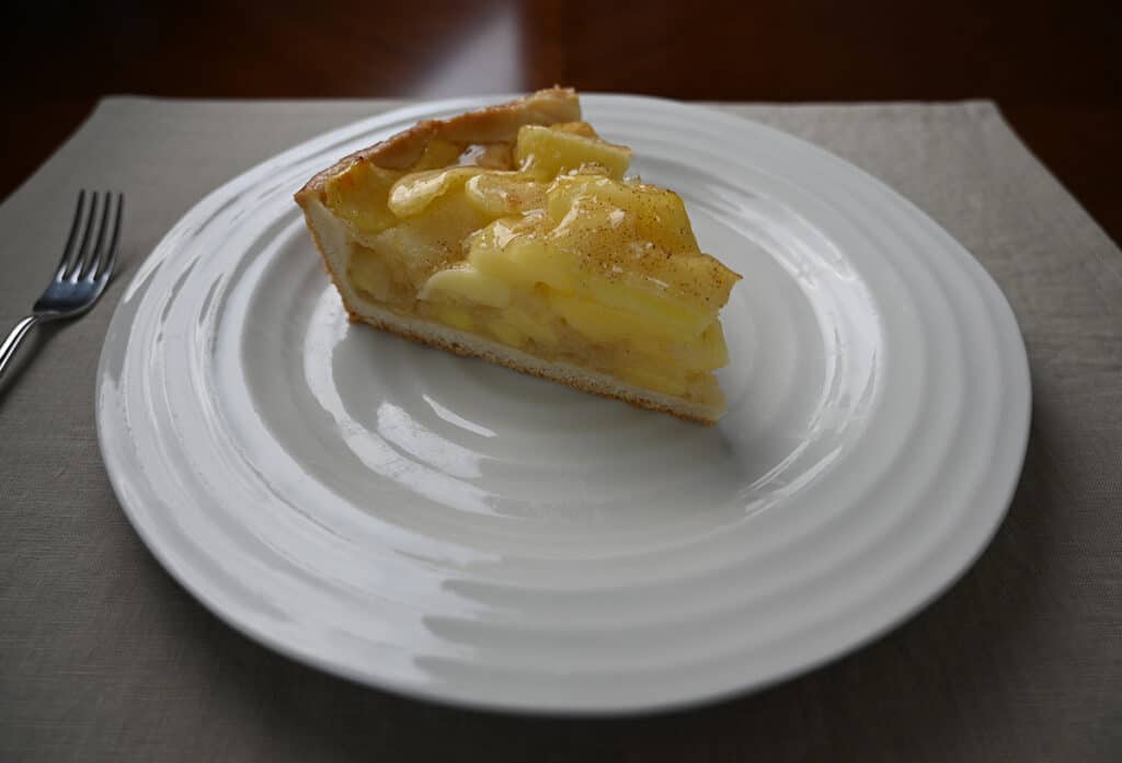 Side view image of one slice of apple cake served on a white plate, you can see how deep the cake is.