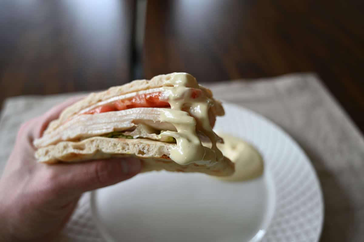 Closeup image of a sandwich dipped in sauce being held close to the camera.