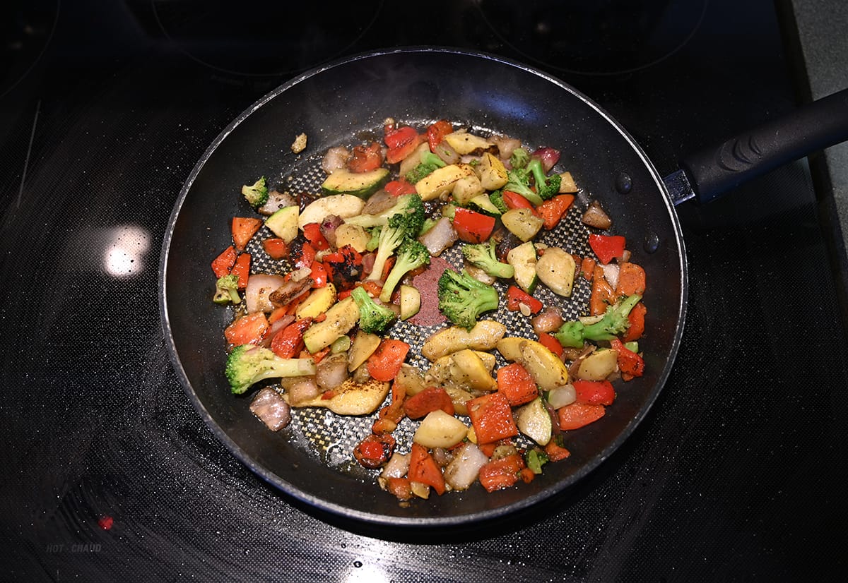 Top down image of the frozen vegetables being cooked on a stovetop in a frying pan.