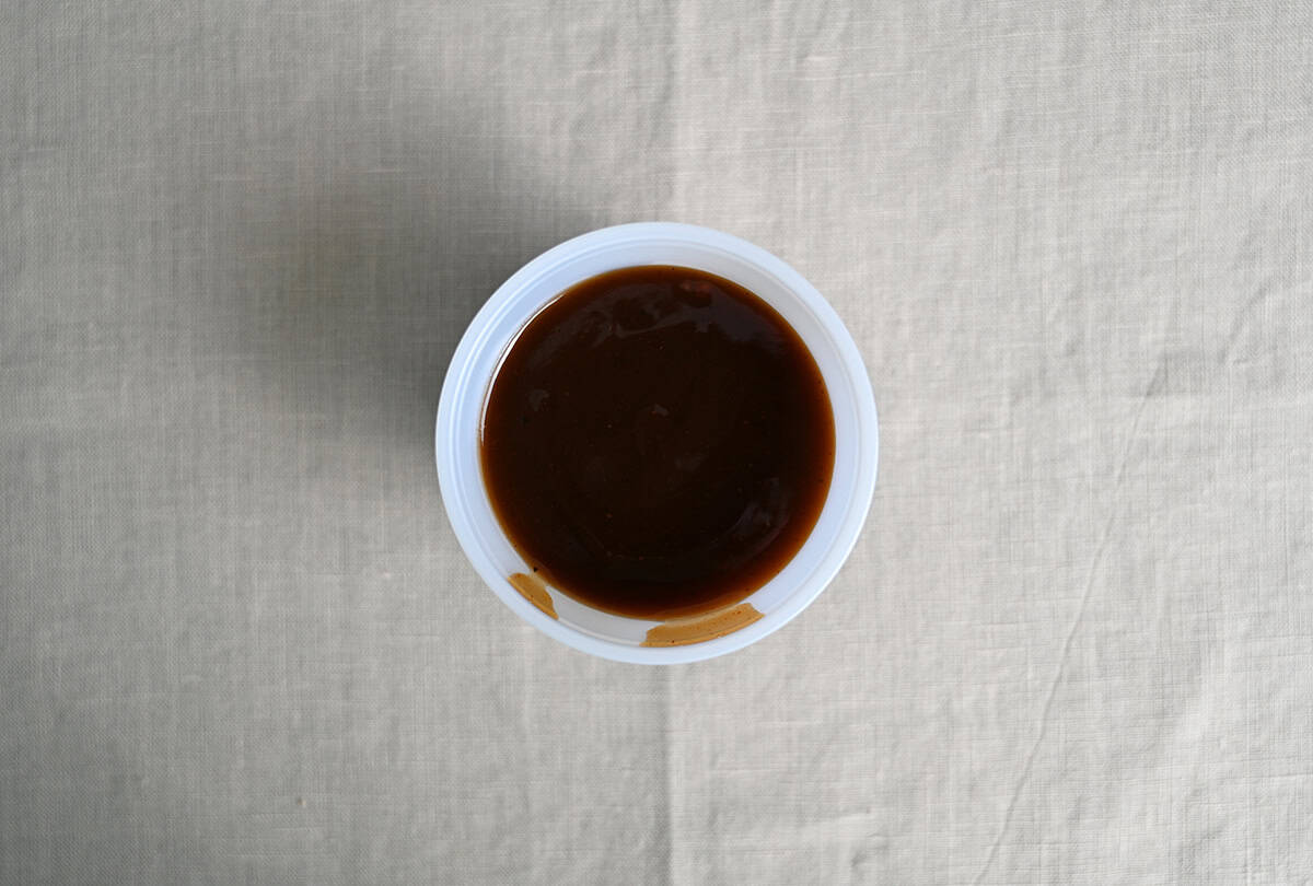 Top down image of an open container of barbecue sauce sitting on a table.