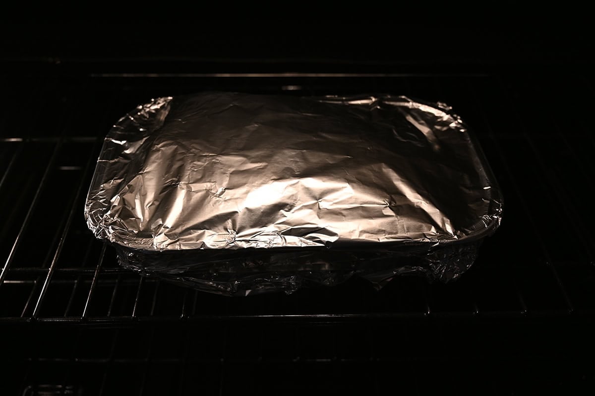 Image of the tray of ribs covered with foil heating in the oven.