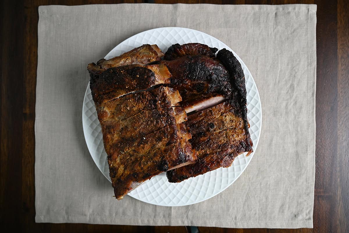 Top down image of a white plate with a few slabs of cooked ribs on the plate.