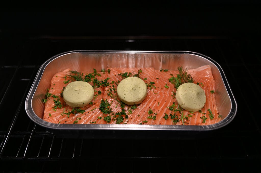 Sideview top down image of the tray of raw salmon sitting on the middle rack of an oven being cooked.