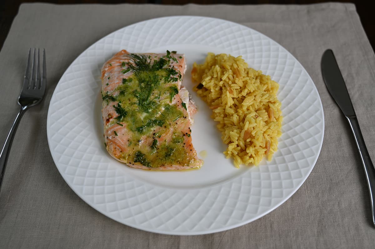 Side view top down image of a plate with a piece of salmon on it beside a side of couscous.