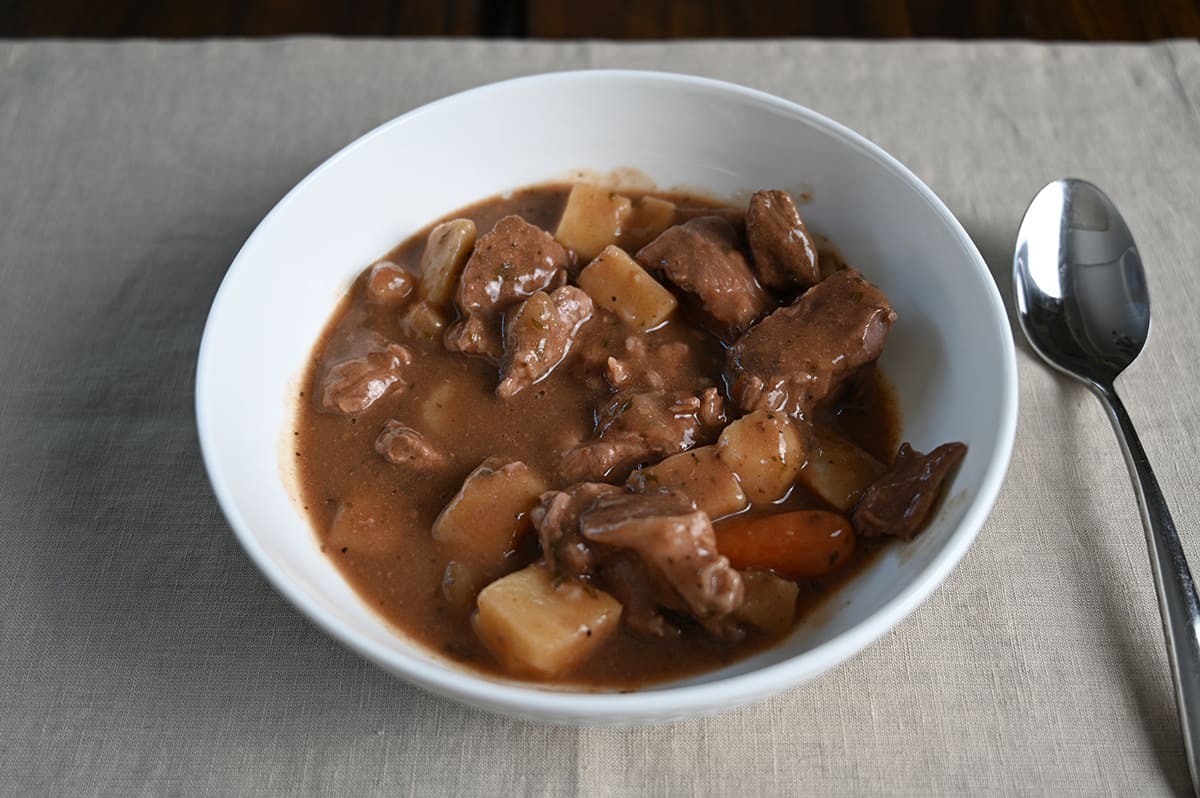 Image of a bowl of stew on a green placemat beside a spoon.