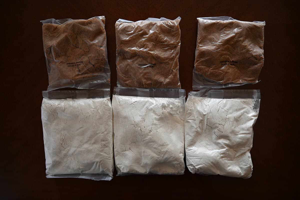 Top down image of three unopened pouches of cake mix and three pouches of topping to make the cake.