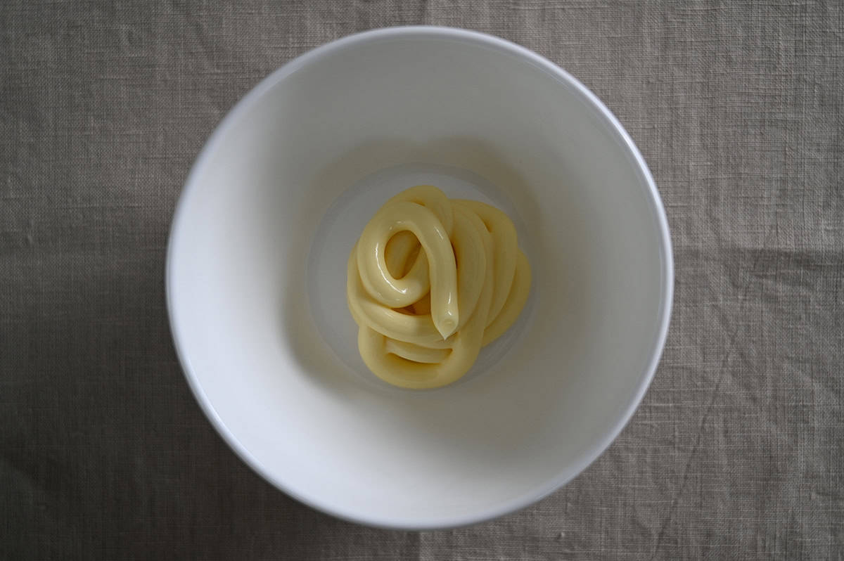 Top down image of a bowl with Kewpie mayo squirted into the bowl so you can see the texture and color. 