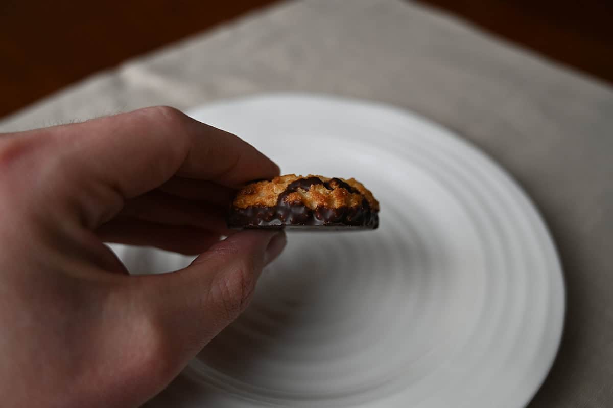 Closeup sideview image of a hand holding one Poppie's cookie on it's side so you can see how big the cookie is.