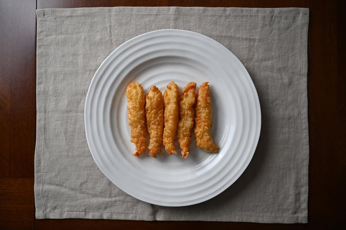 Top down image of five tempura shrimp cooked and served on a white plate. 