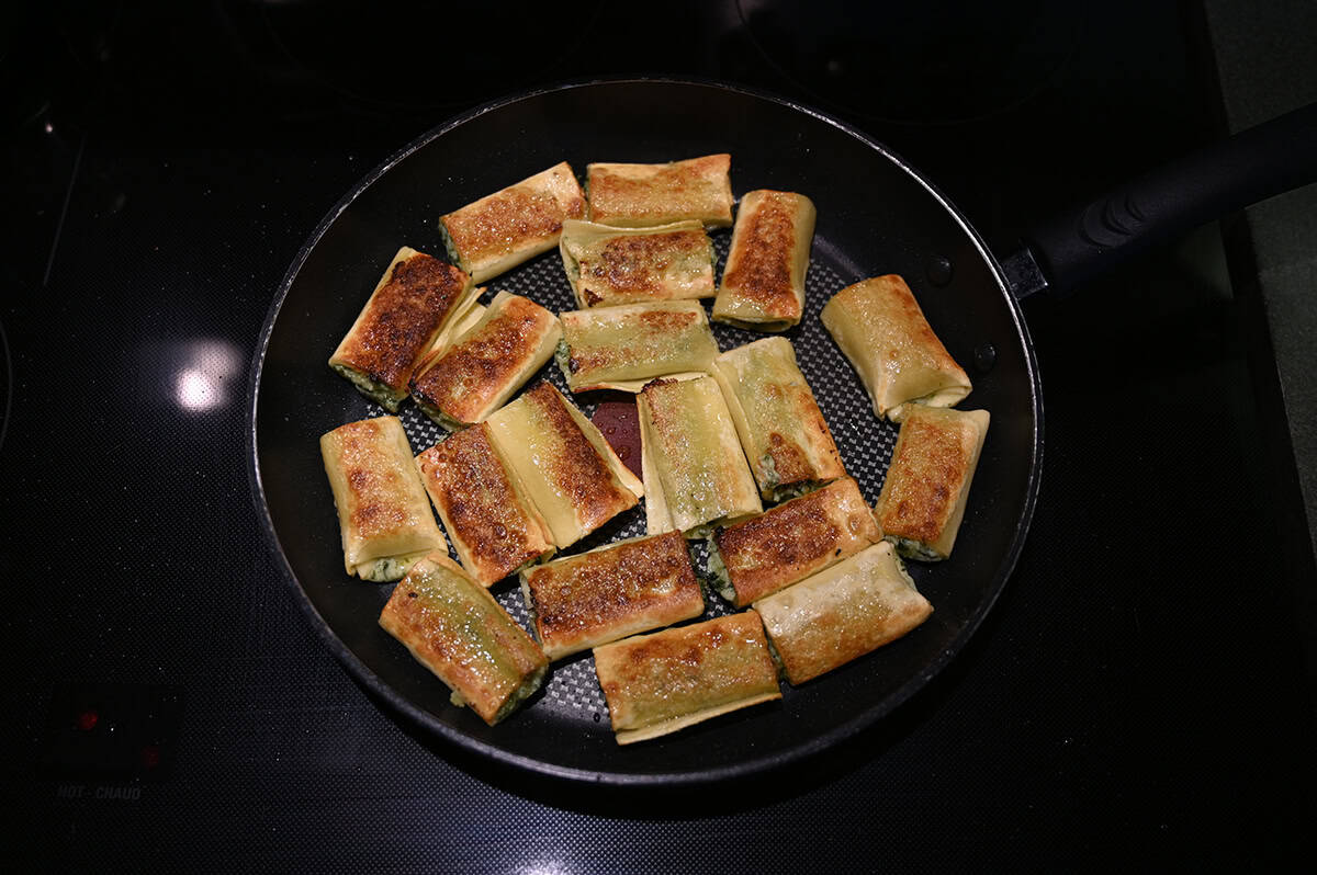 Top down image of cannelloni being cooked in a frying pan on the stovetop.