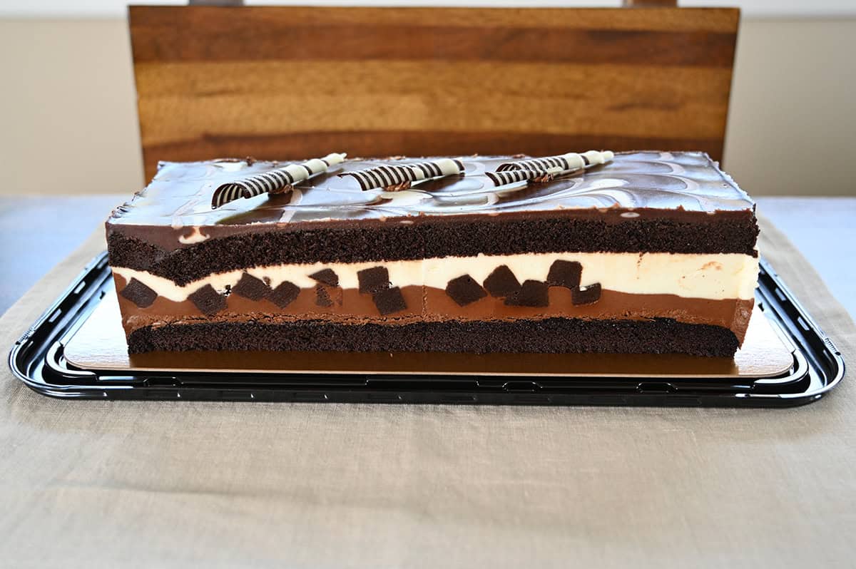 Side view image of the Costco Kirkland Signature Tuxedo Chocolate Mousse Cake opened and sitting on a table, not yet cut.