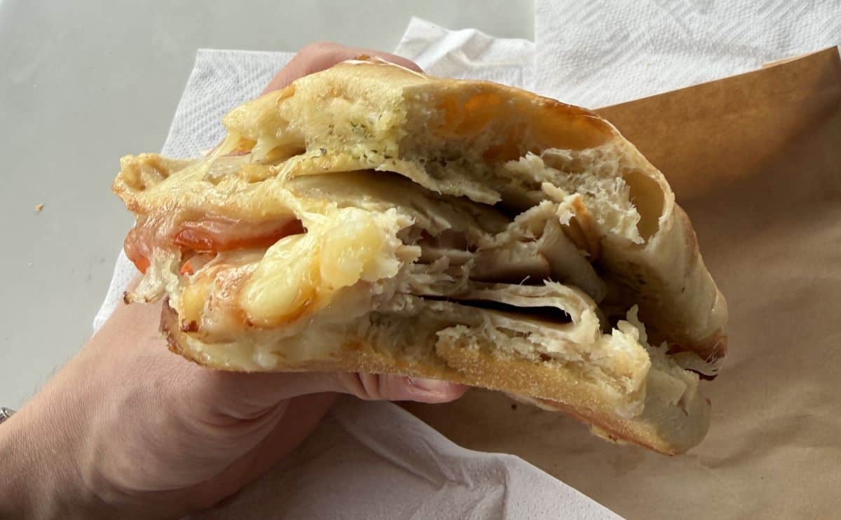 Image of a hand holding the Costco Turkey & Provolone Sandwich close to the camera.