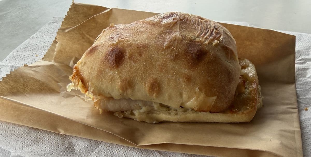 Image of the Costco Food Court Turkey & Provolone Sandwich unwrapped and sitting on a brown paper bag.