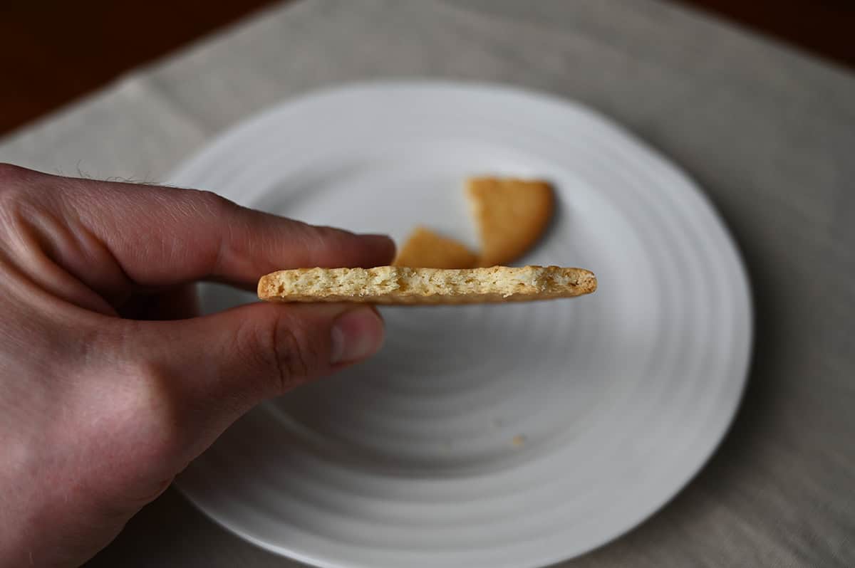 Image of a hand holding on biscuit close to the camera with a few bites taken out so you can see the center of the cookie.