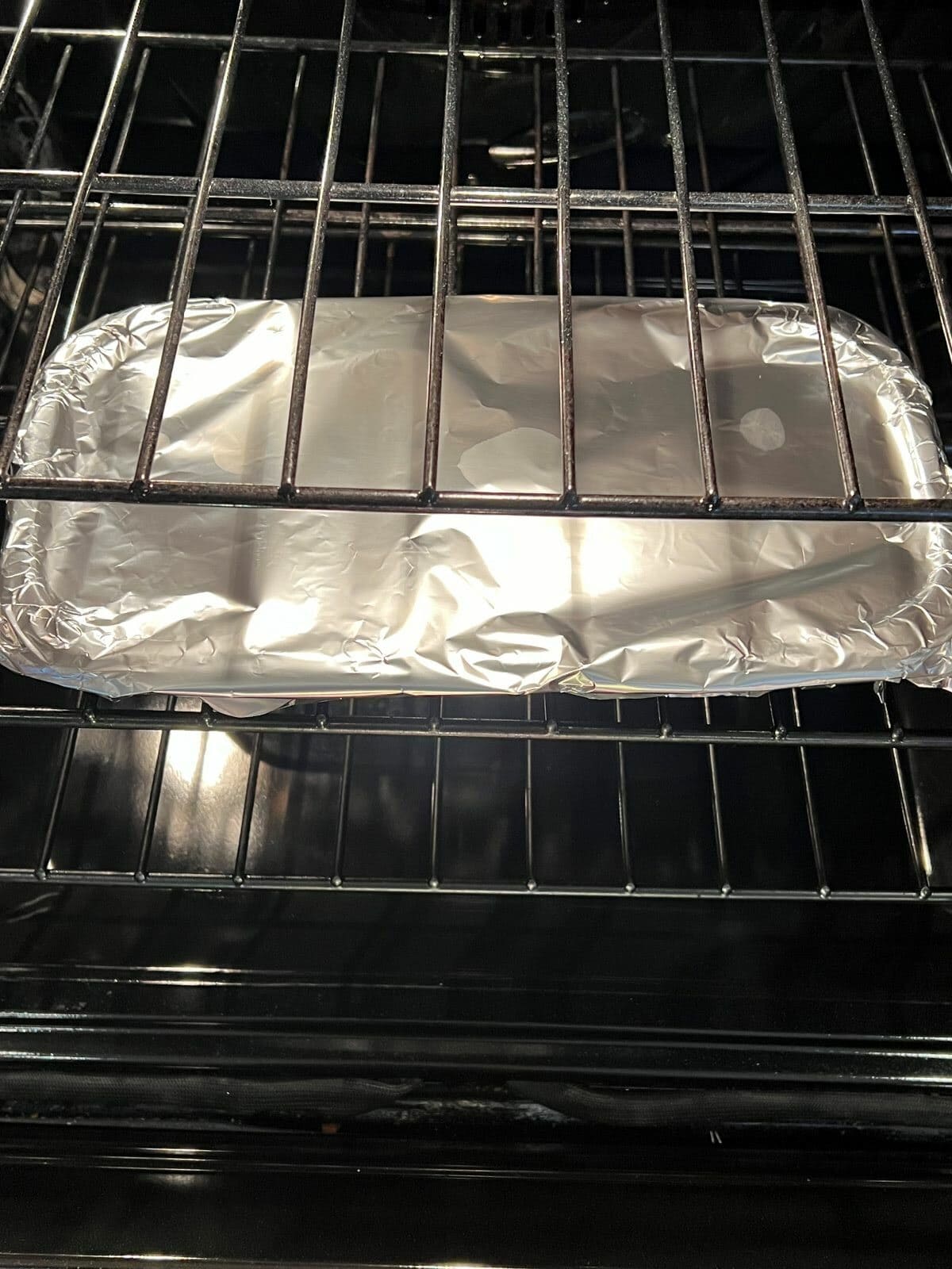 Image of a tray covered in aluminum foil cooking in an oven.