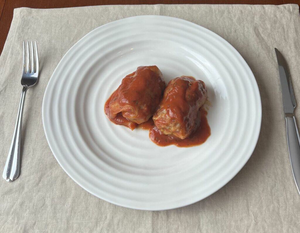 Image of two cabbage rolls sitting on a white plate.