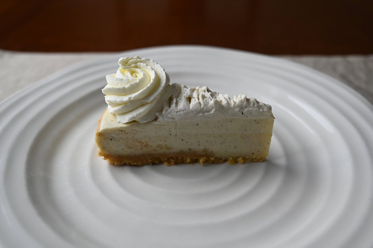 Image of one slice of vanilla bean cheesecake served on a white plate.