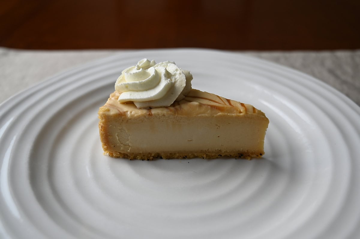 Image of one slice of Dulce De Leche Caramel Cheesecake served on a white plate.