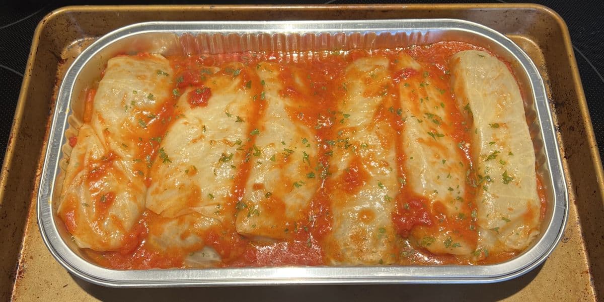 Image of a cookie tray with the tray of cabbage rolls on it after being cooked in the oven.