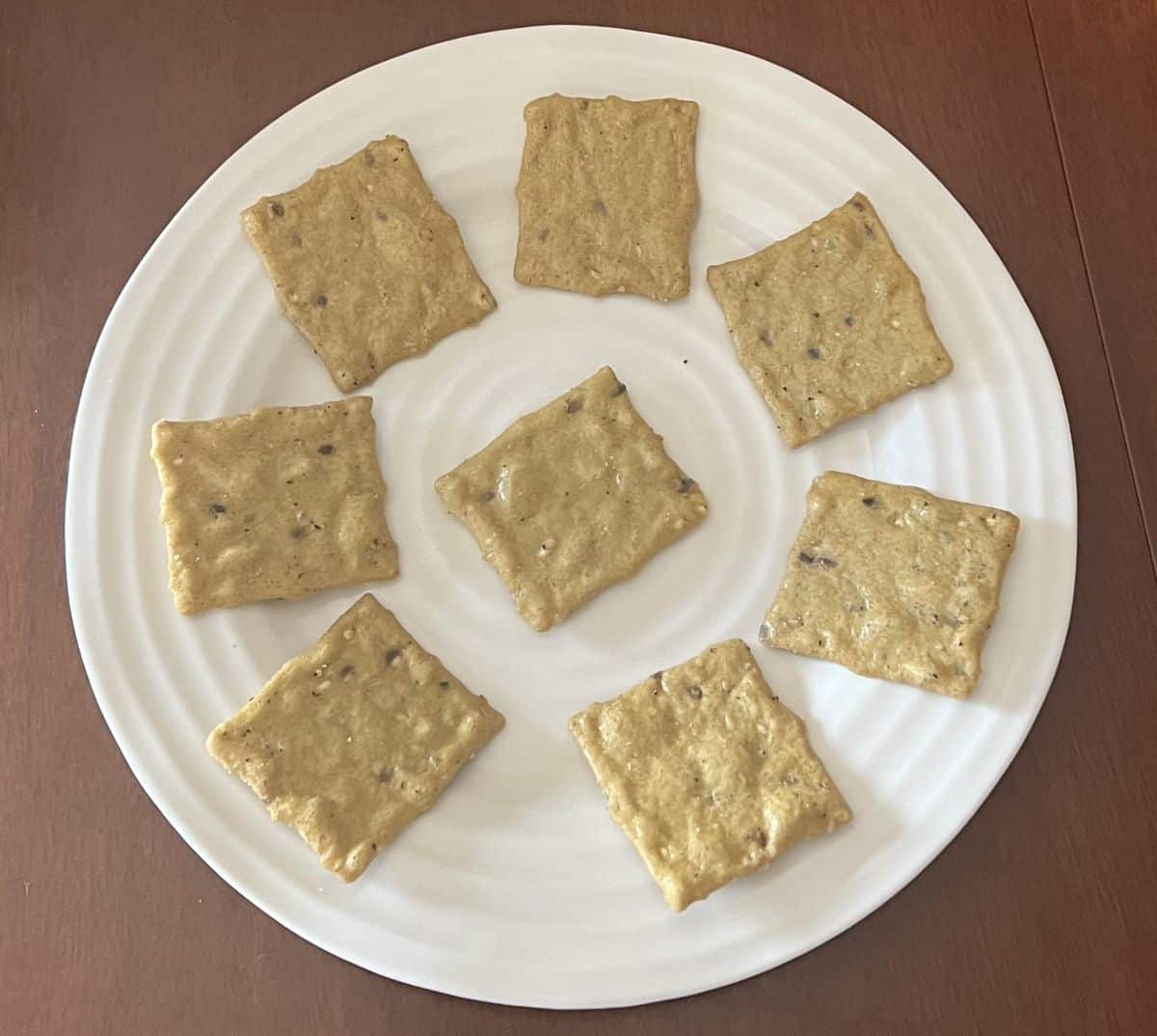 Top down image of avocado crackers served on a white plate. 