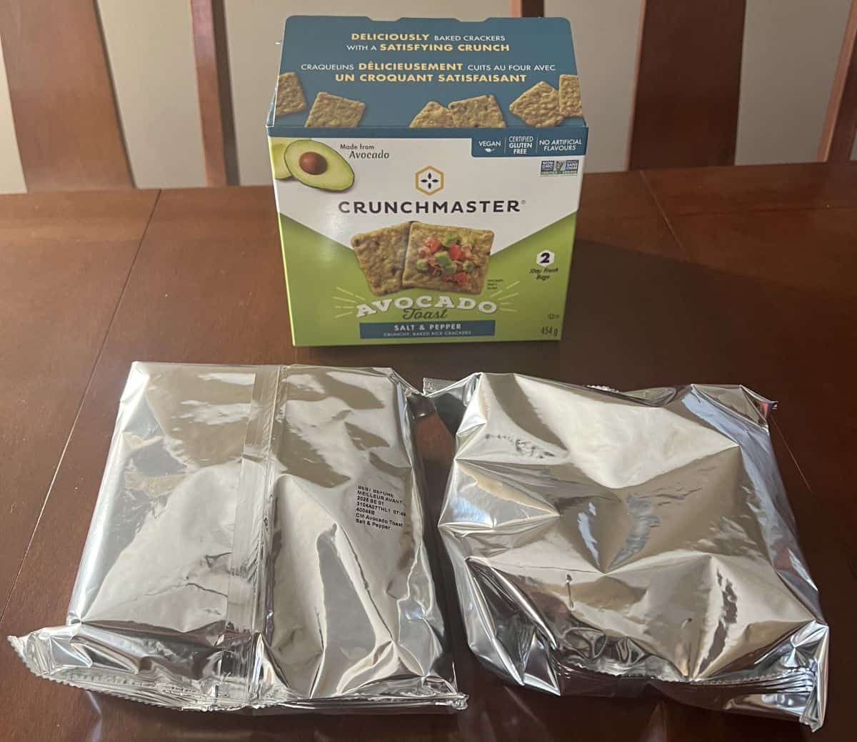 Image of two sealed bags of crackers unopened in front of the box for the crackers. 