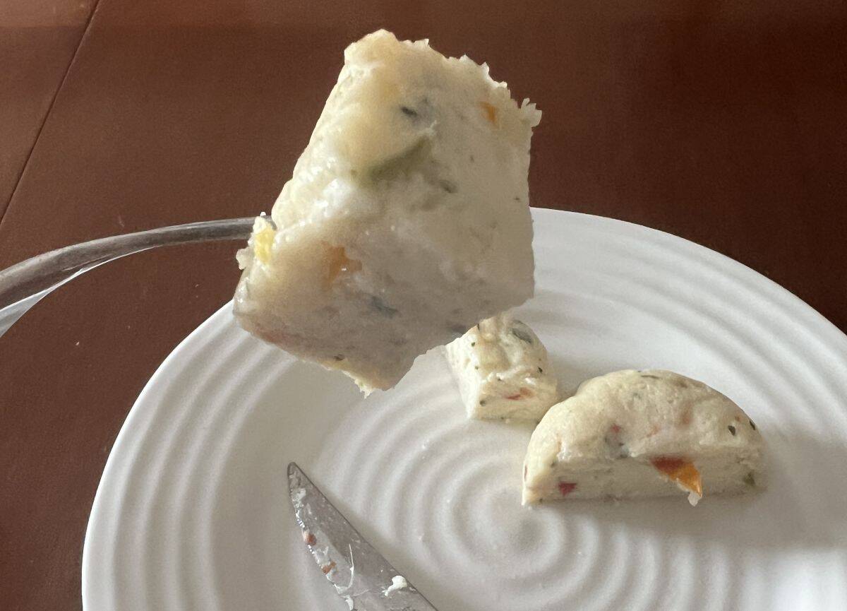 Image of  a fork with a bite of the egg white with cheese & roasted red pepper egg bite on it.