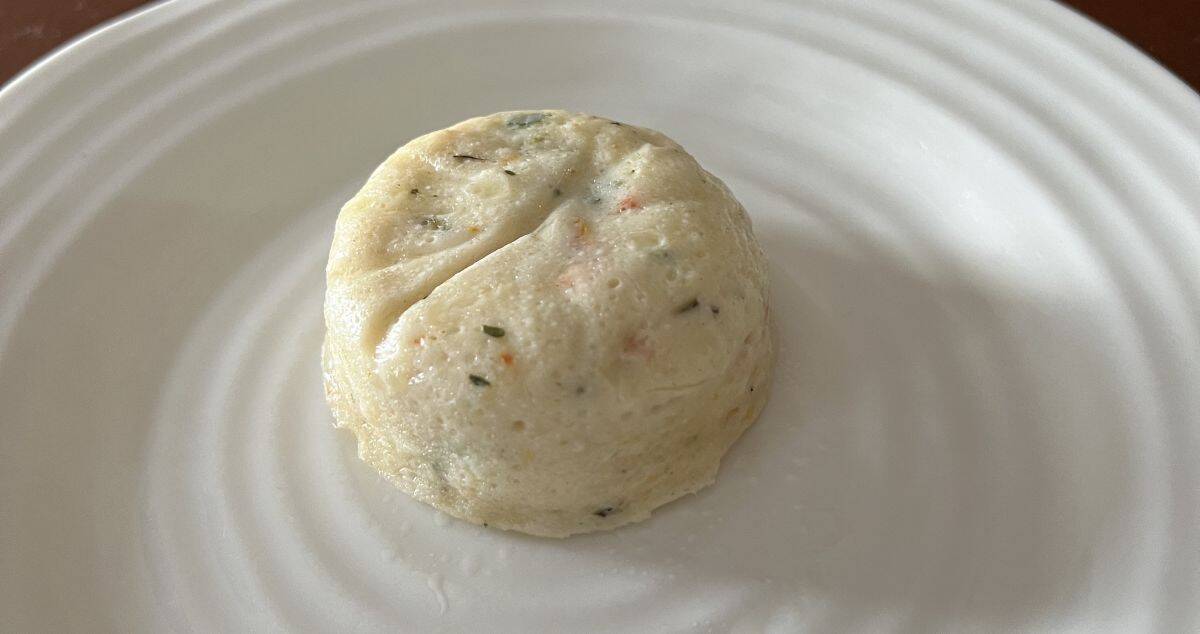 Image of one egg white with cheese & roasted red pepper egg bite served on a white plate. 