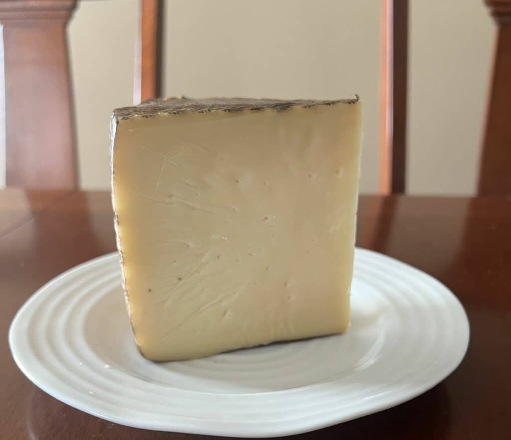 Image of a large block of manchego cheese served on a white plate. 