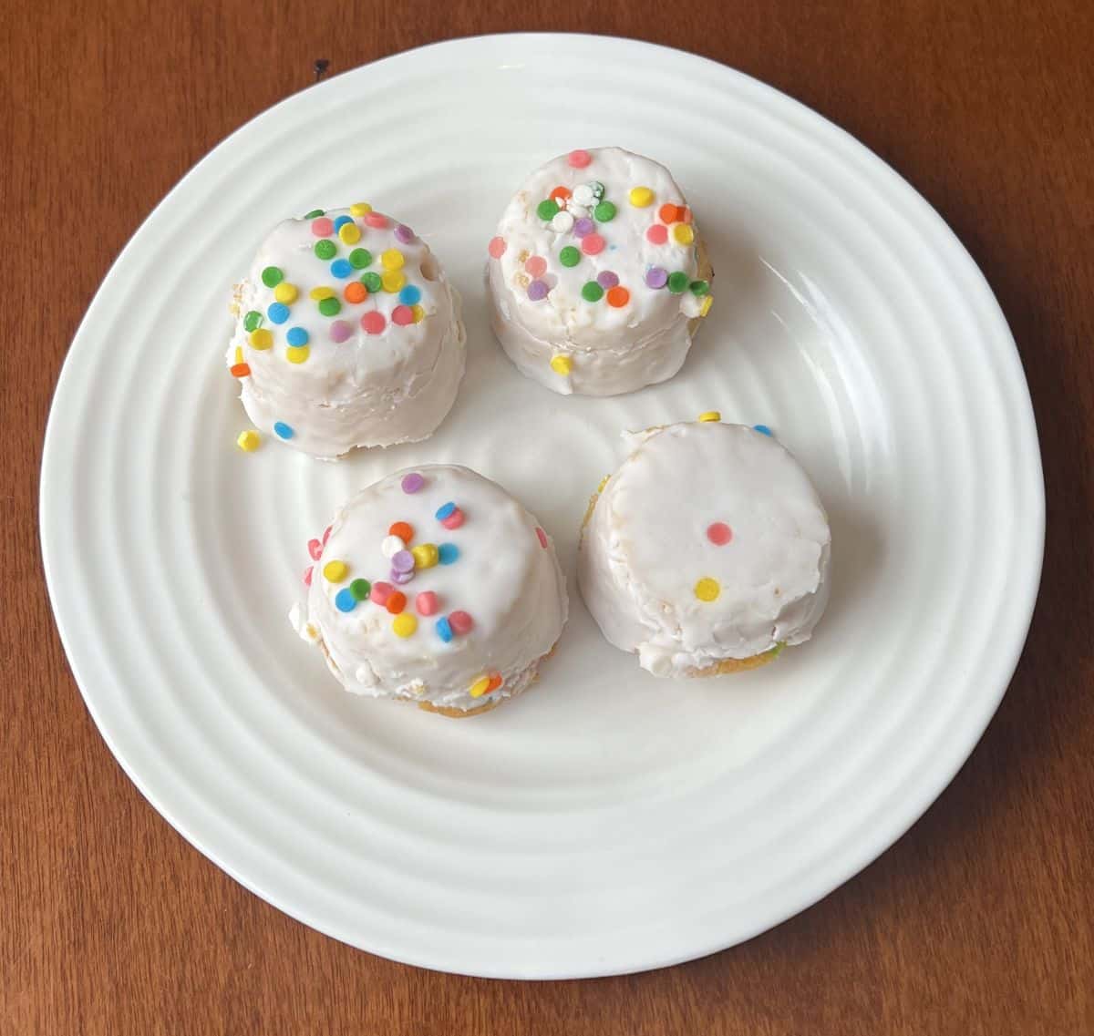 Top down image of four cake bites served on a white plate.