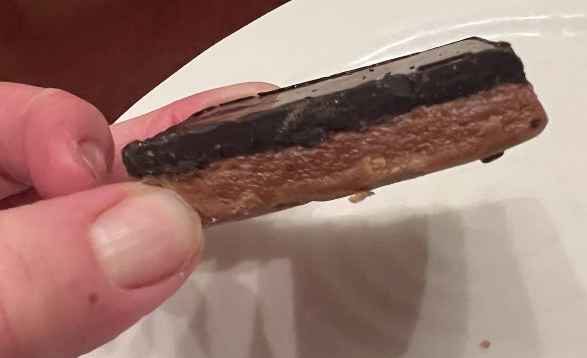 Closeup image of a hand holding one peanut butter Mid-Day Square close to the camera.