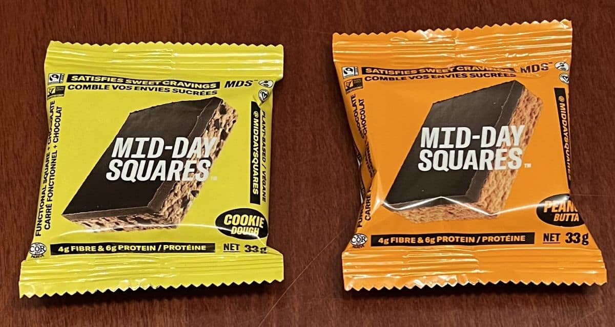 Image of one wrapped cookie dough and one wrapped peanut butter Mid-Day Square sitting on a table.