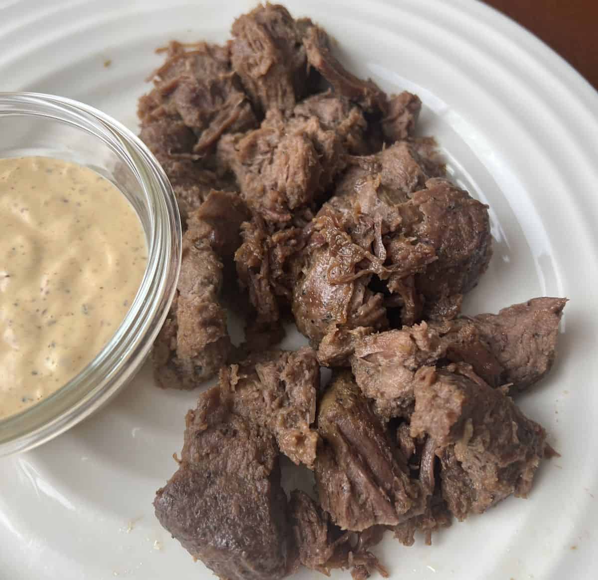 Closeup image of the steak bites heated up and served on a white plate.