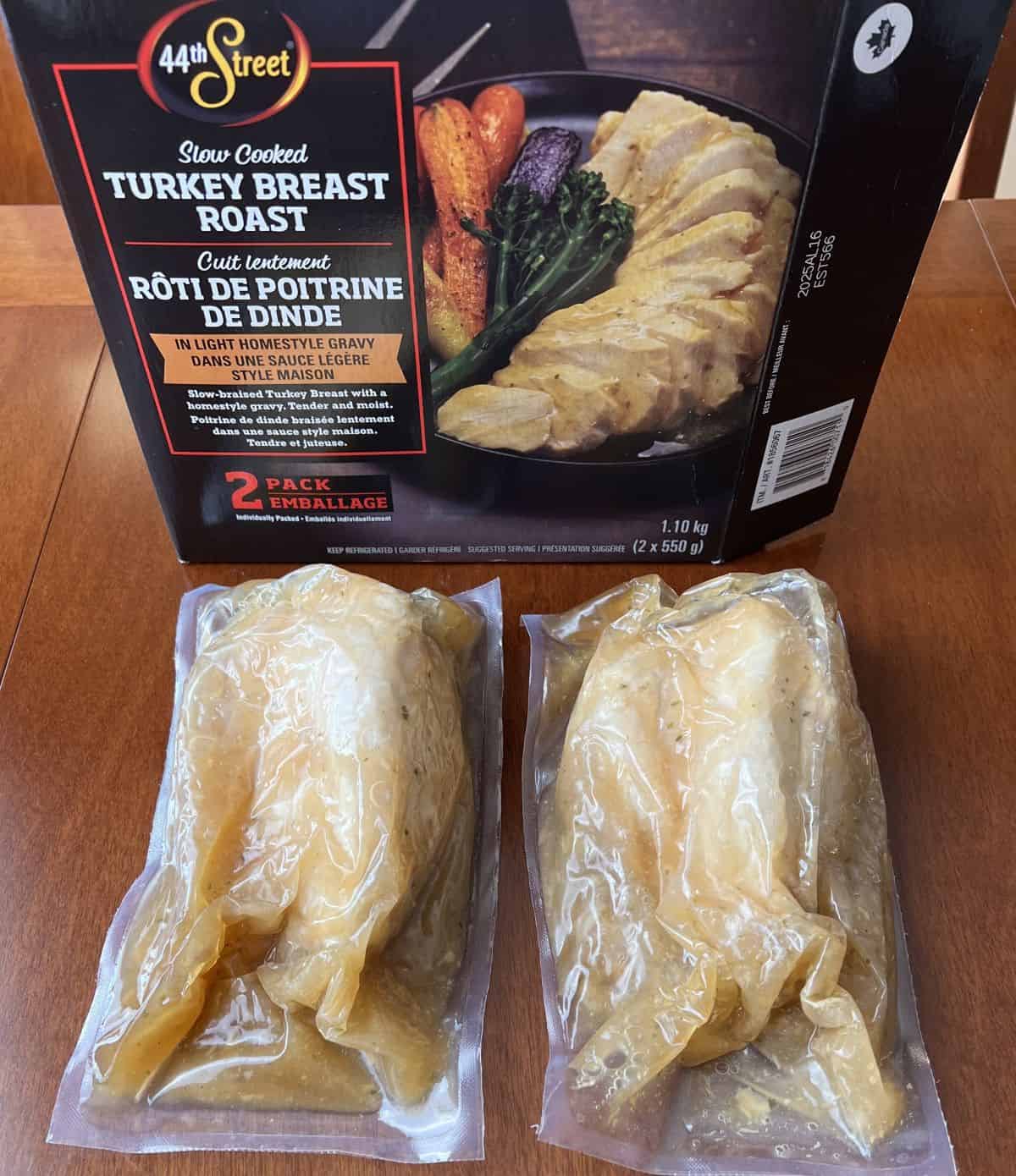 Image of two turkey breasts vacuum sealed sitting on a table in front of a box. 