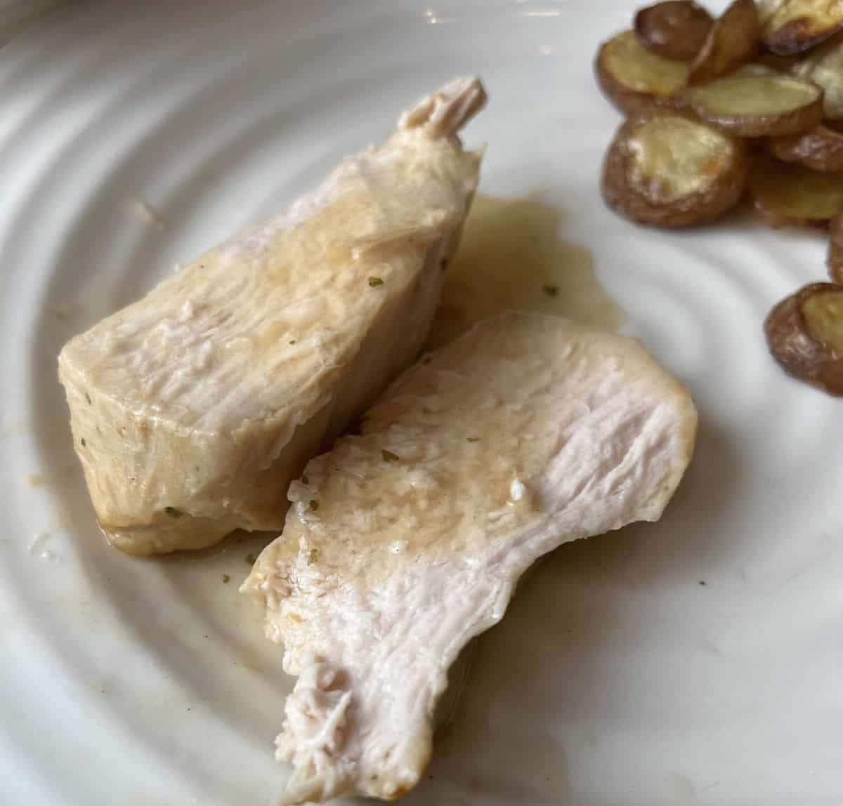 Closeup image of a turkey breast cooked and served on a white plate. 