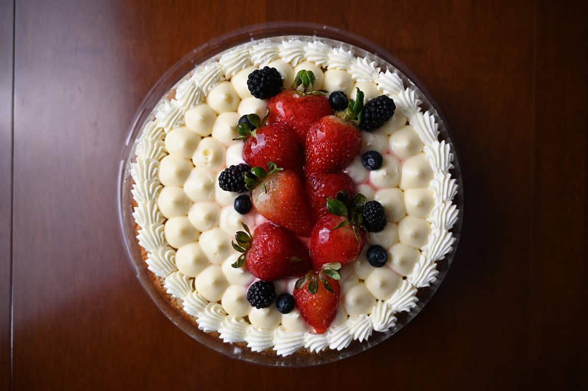 Top down image of the top of the Chantilly Cake showing it has strawberries and blueberries on top of a cream icing. 