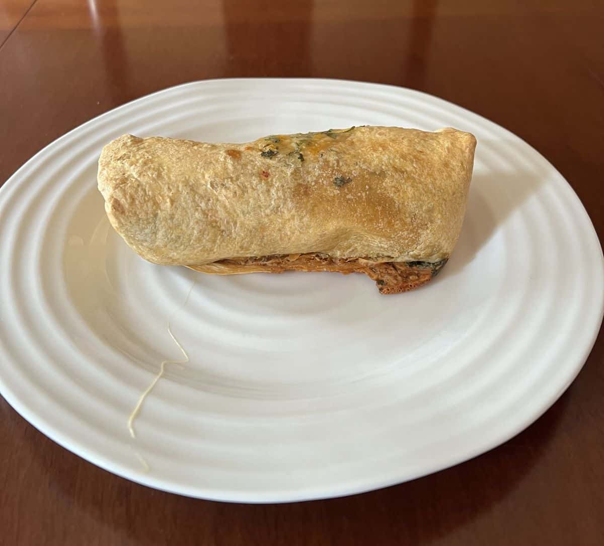Image of one burrito served on a white plate after being heated.