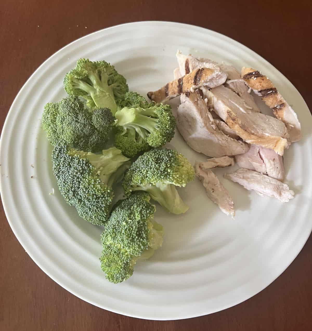 Image of the chicken strips served on a white plate beside a side of broccoli. 