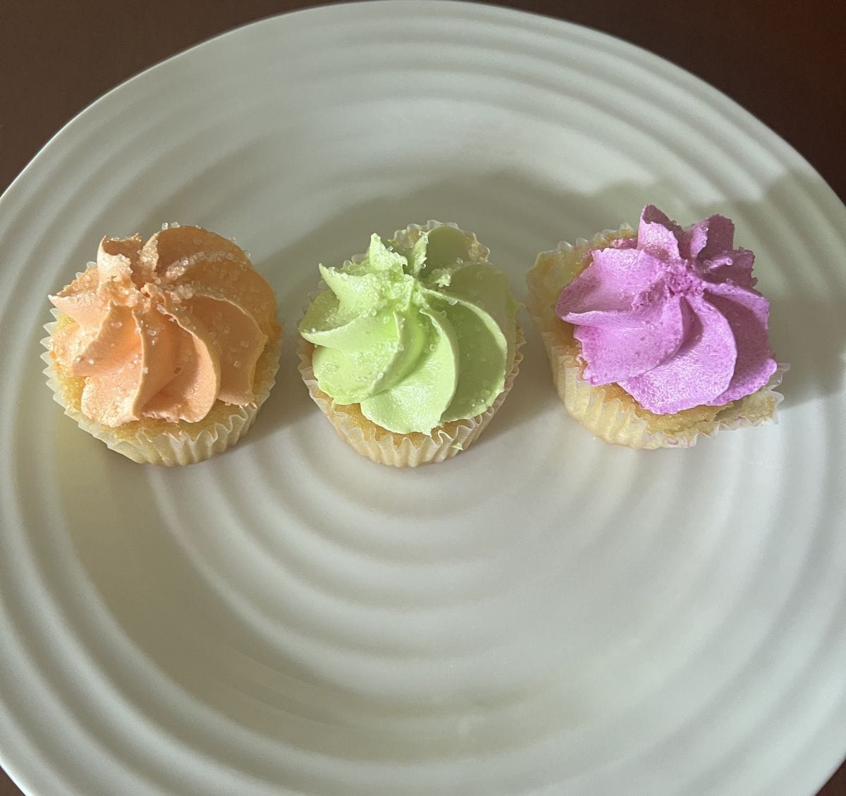 Image of three cupcakes served on a white plate. 