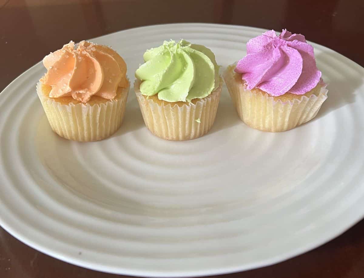 Image of an orange, lime and raspberry cupcake served on a white plate.