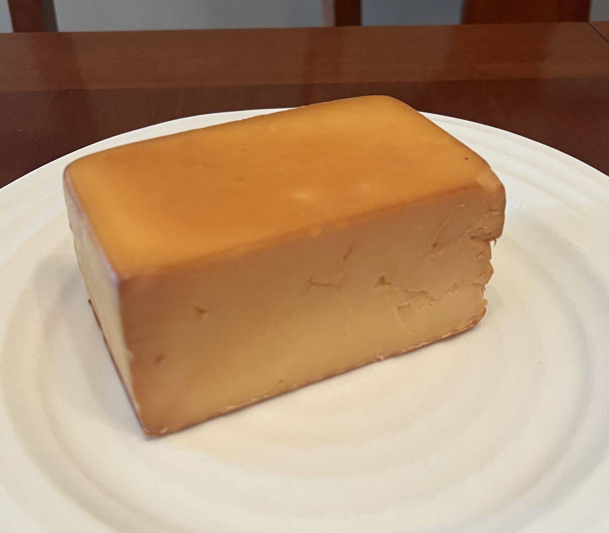 Side view image of a block of cheddar served on a white plate. 